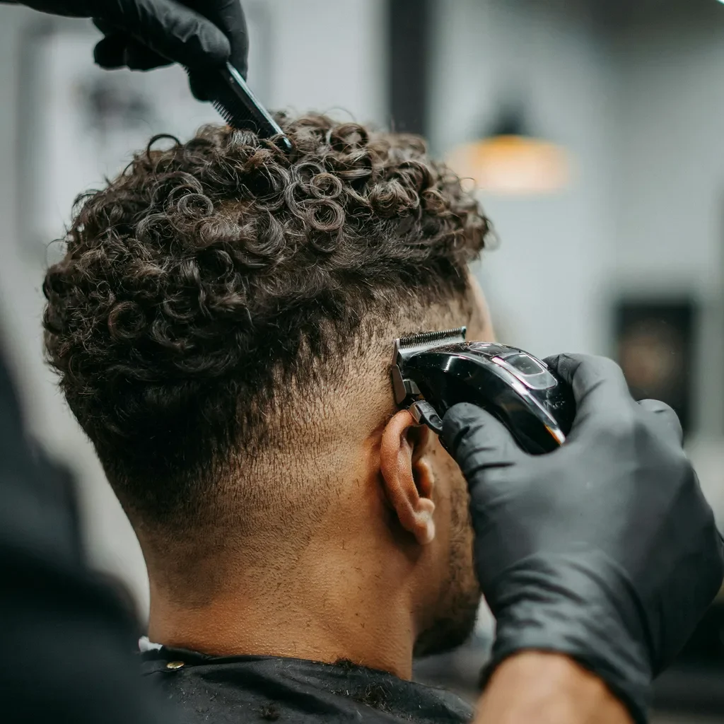 Barber fading a client's curly textured hair with clippers