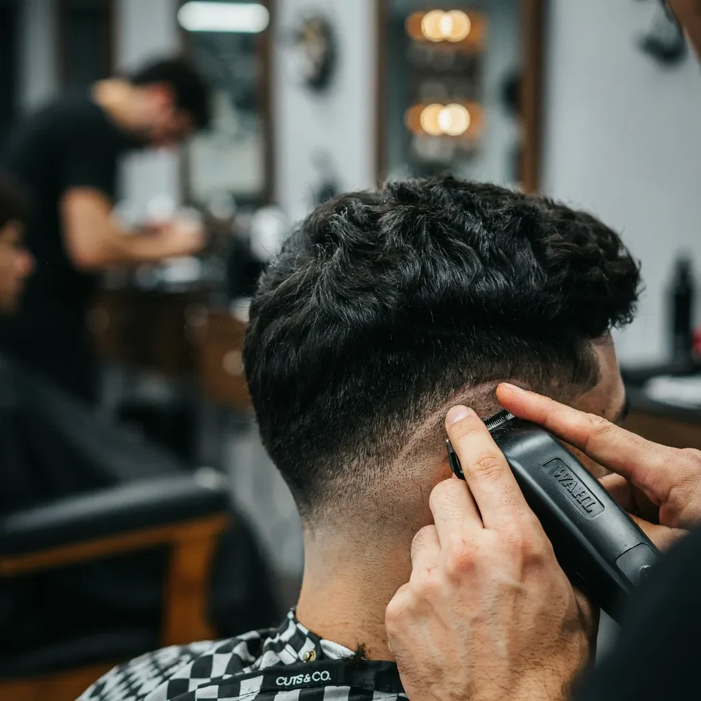 barber blending a mid fade into thick dense hair
