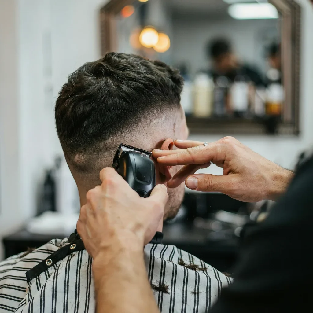 Barber's hand using a flicking motion with clippers to blend a fade