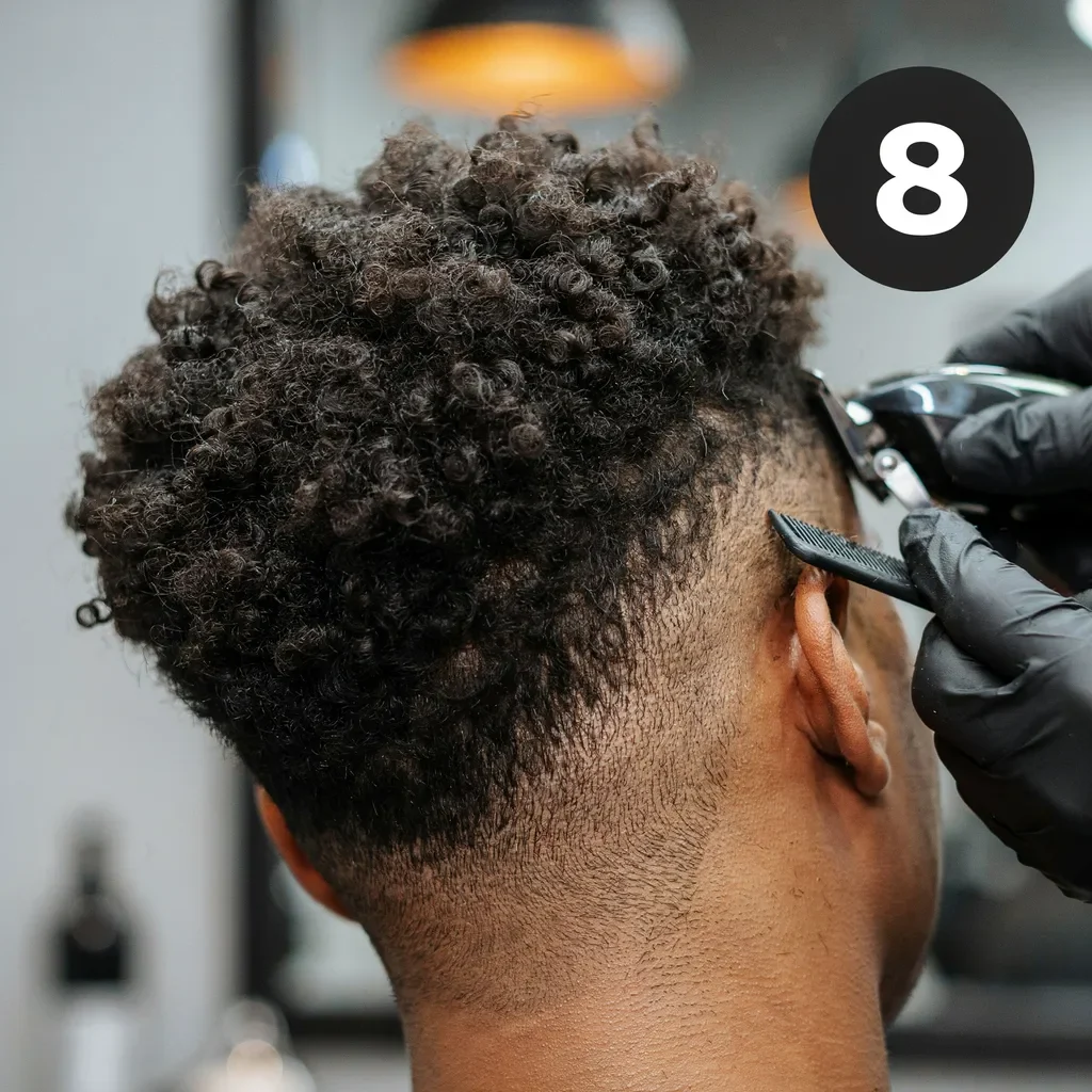 Barber fading curly textured hair at a barbershop station