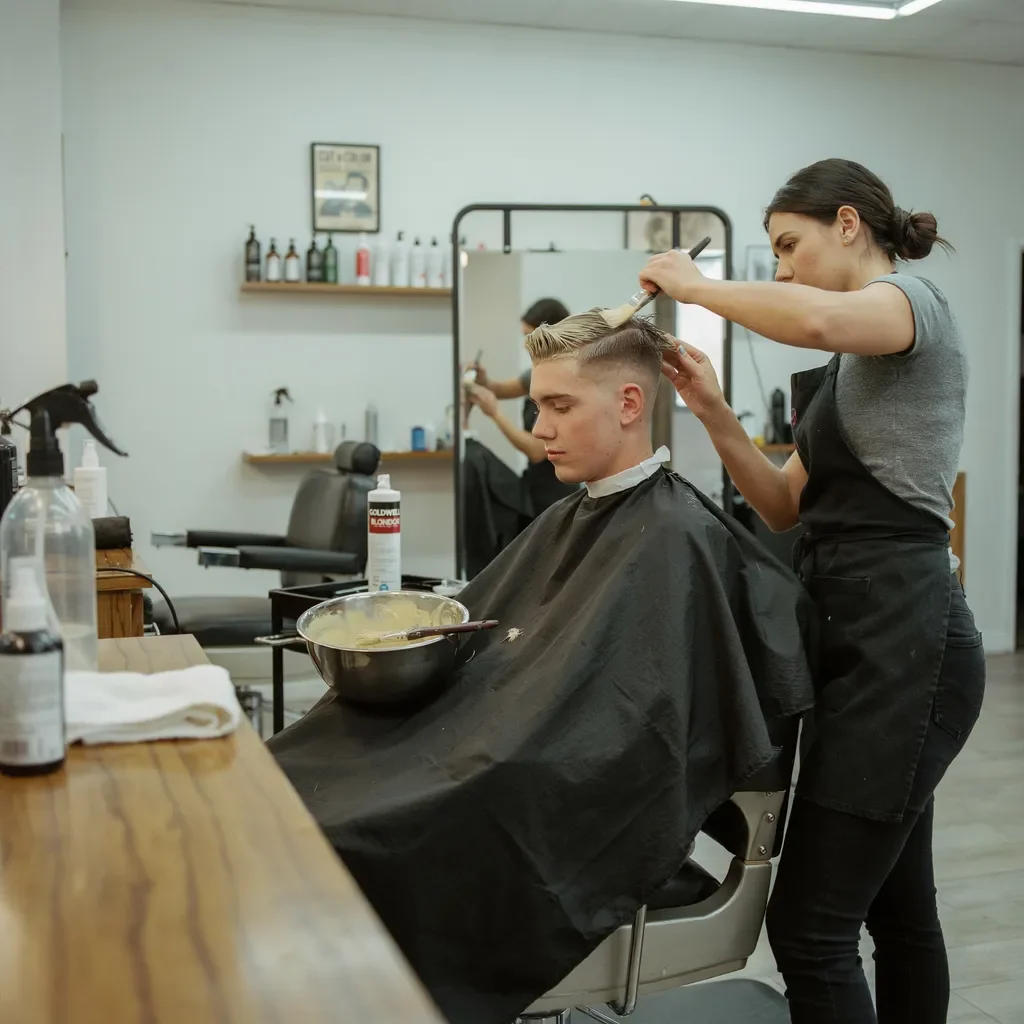 colorist working on a bleached top with a mid fade