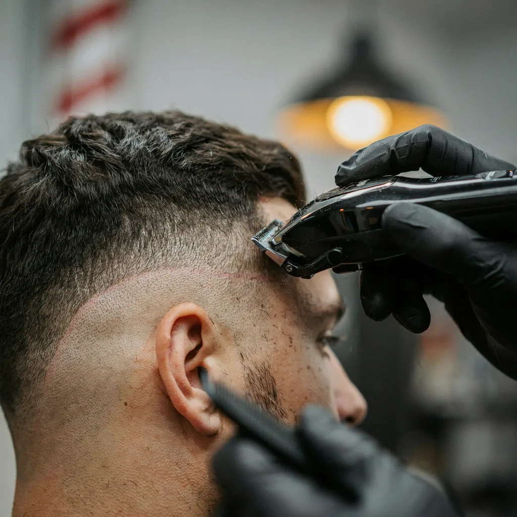 Macro shot of a barber's clippers blending hair at the temple