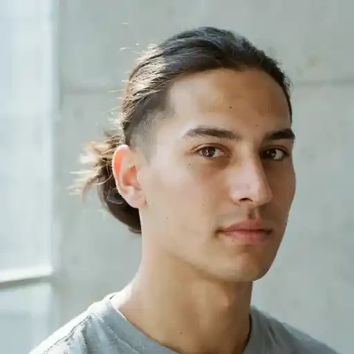 long hair tied into a small ponytail with a mid fade