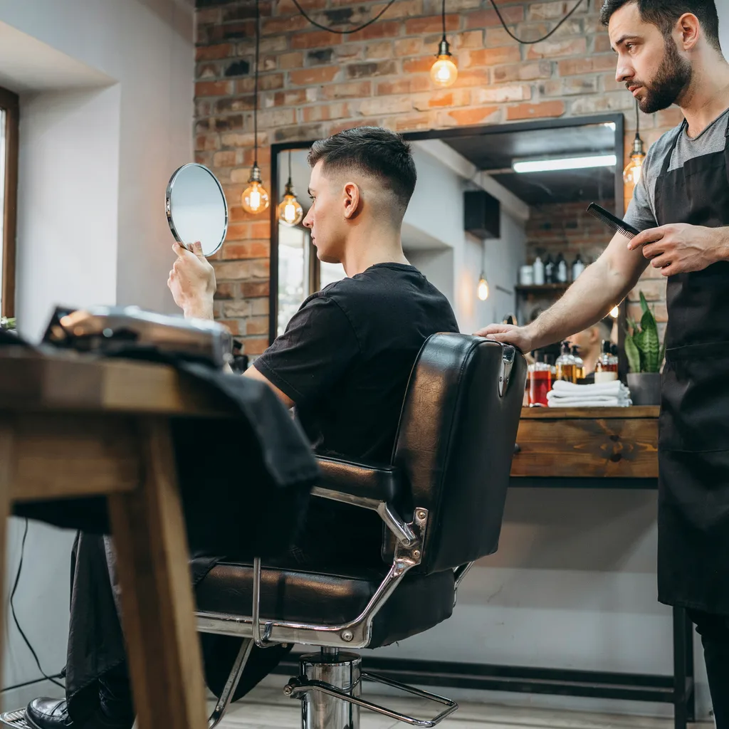 Client checking the back of his mid fade haircut with a hand mirror