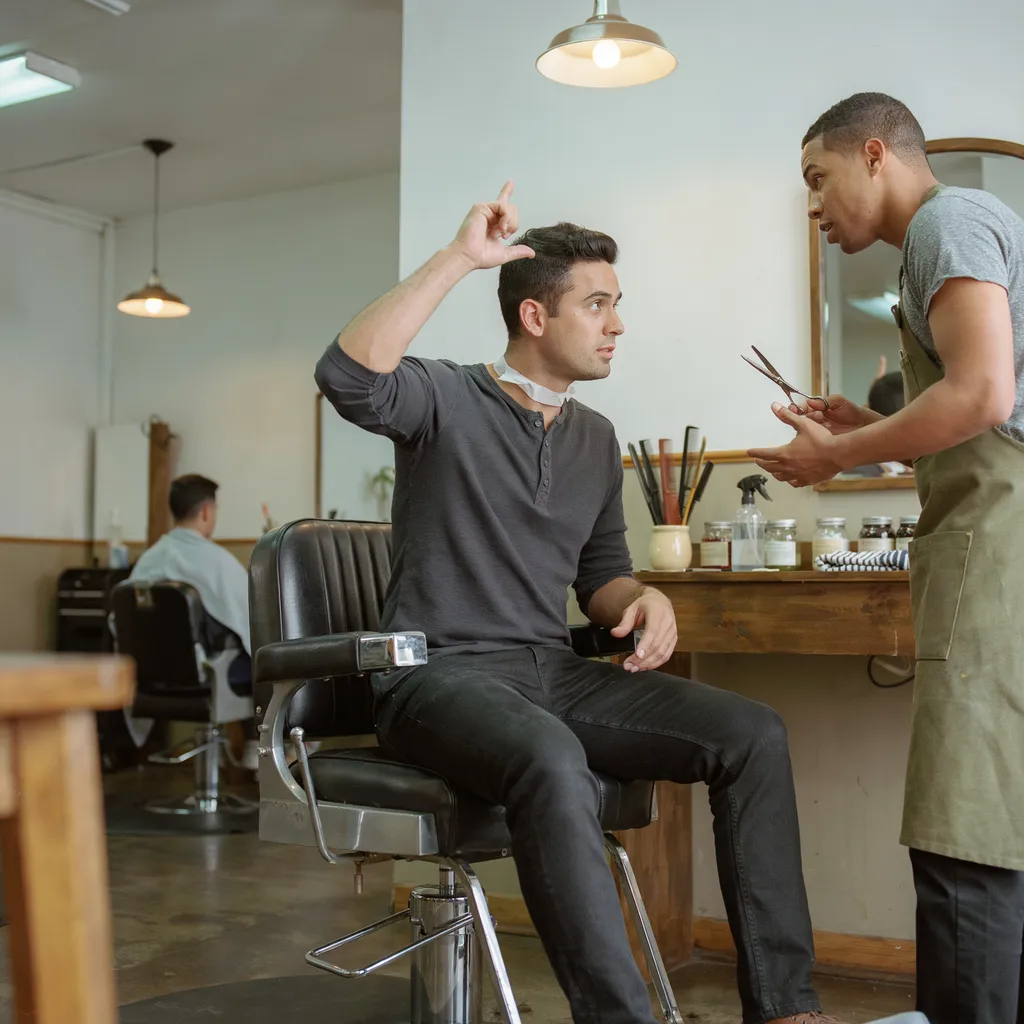 Client gesturing to show the top hair length he wants for his mid fade