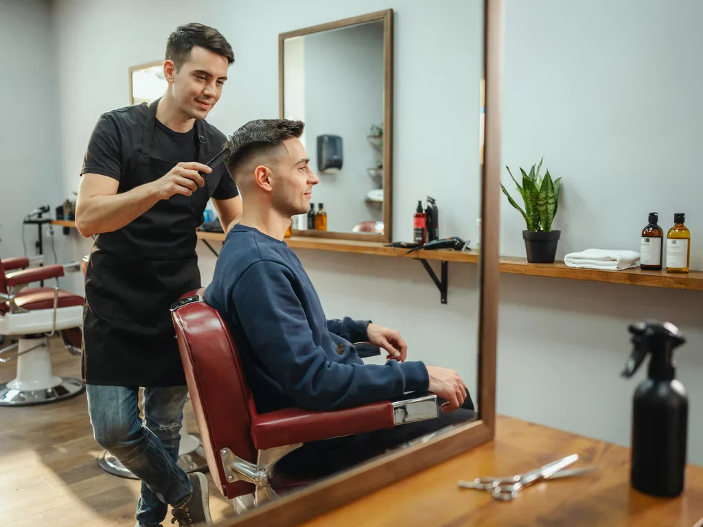 Barber and client looking at a finished mid fade haircut in the mirror