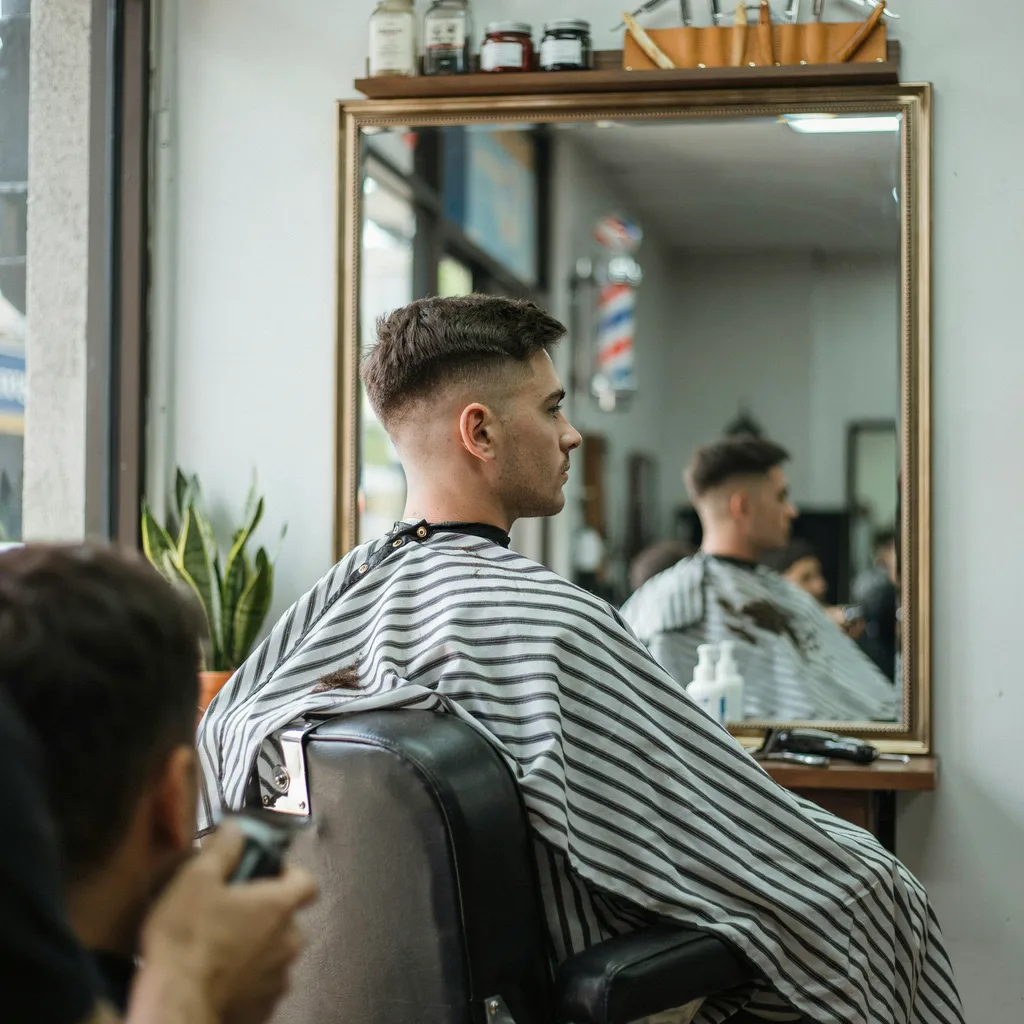 Client checking his mid fade side profile in a barbershop mirror