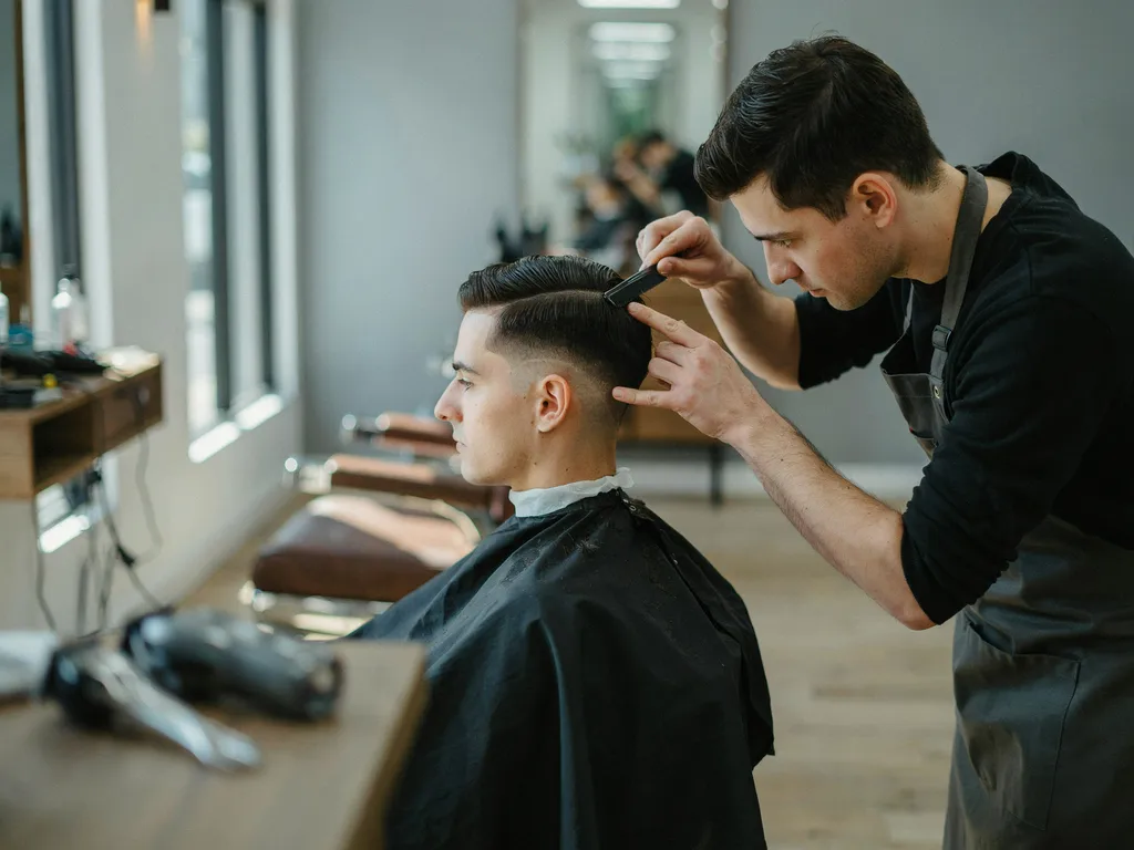 Barber marking the temple level starting point of a mid fade