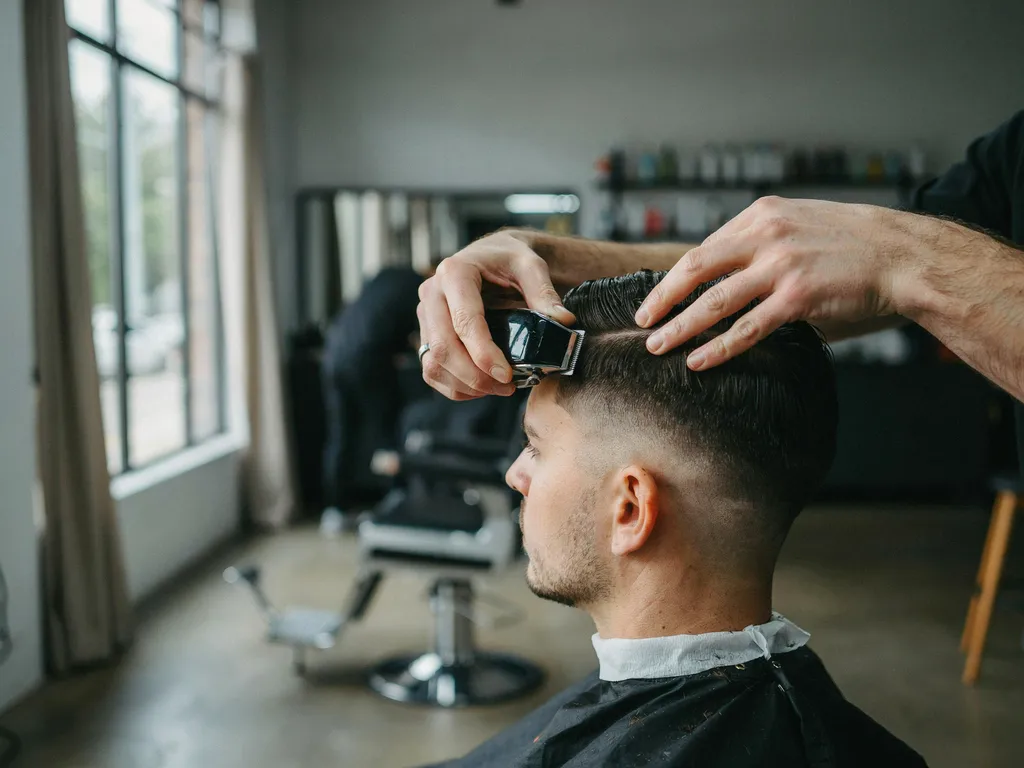 Barber blending a fade haircut with clippers close focus on technique