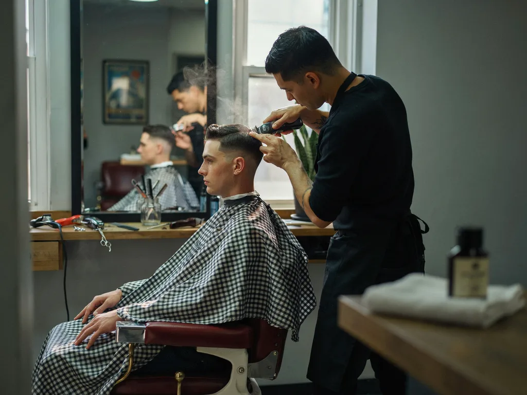 Barber finishing a sharp high contrast fade haircut in a barbershop chair