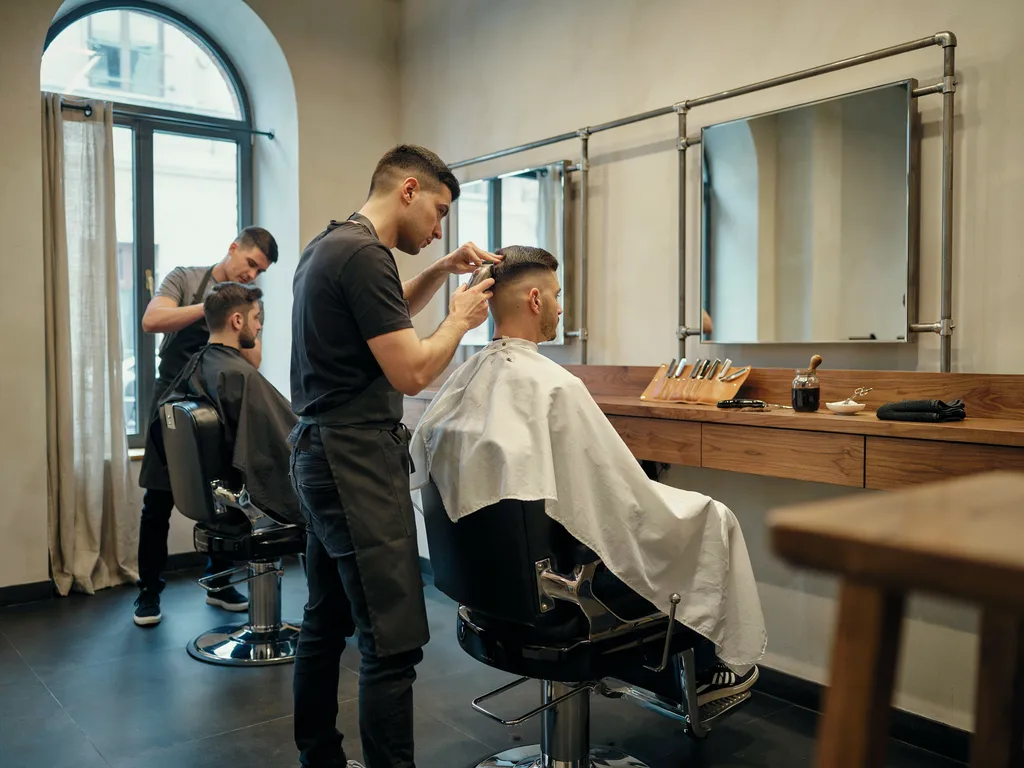 Barber finishing a fade haircut near the temple in a modern barbershop
