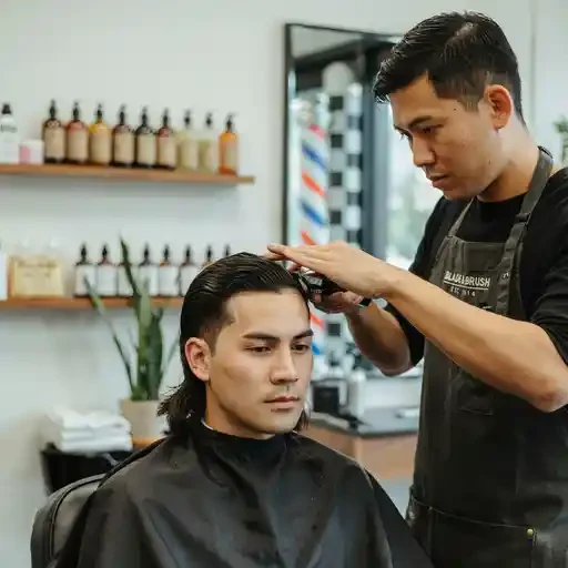 barber fading the sides of a mullet at the temple